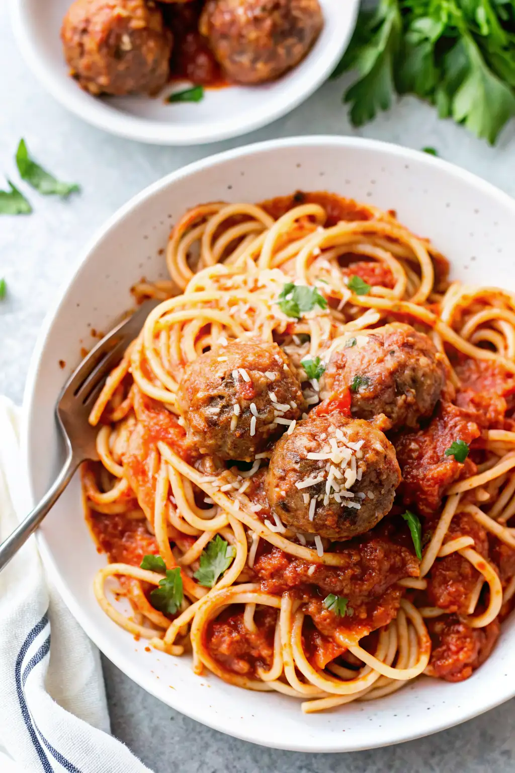 Spaghetti with Meatballs and Tomato Sauce A bowl of spaghetti topped with tomato sauce, meatballs, and grated Parmesan cheese, garnished with fresh parsley.