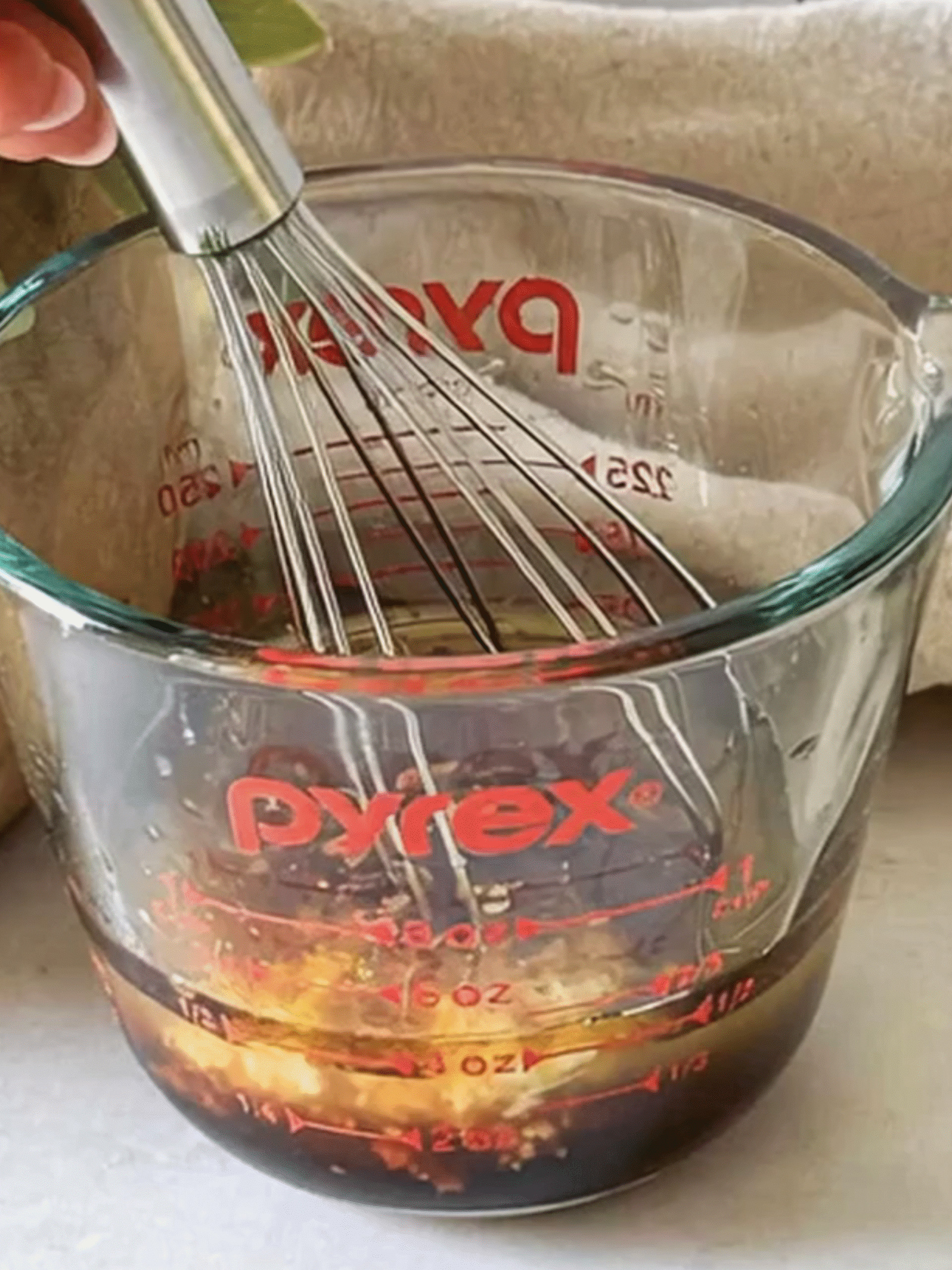 Whisking Asian Crunchy Salad Sesame Ginger Dressing Whisking Asian Crunchy Salad dressing in a glass measuring cup with soy sauce, lime juice, ginger, and sesame oil