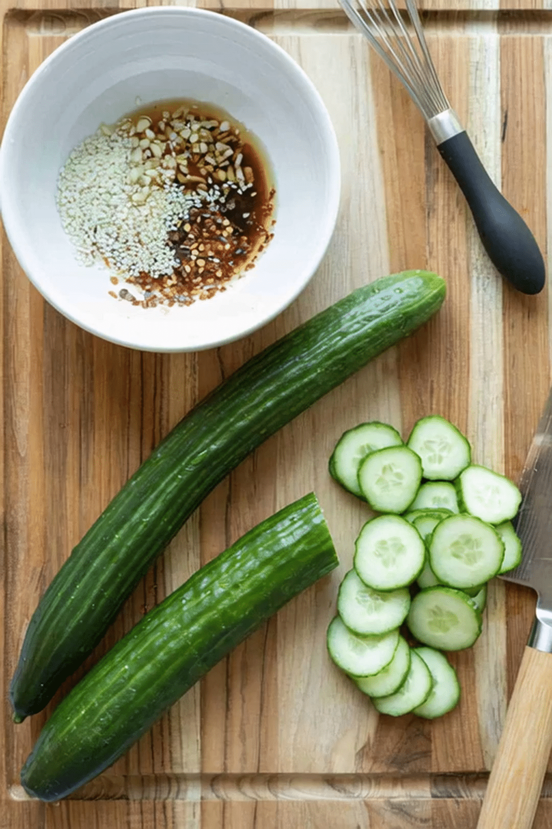 Spicy Cucumber Salad Recipe Ingredients and Prep Fresh cucumbers sliced on a cutting board with spicy dressing ingredients in a white bowl