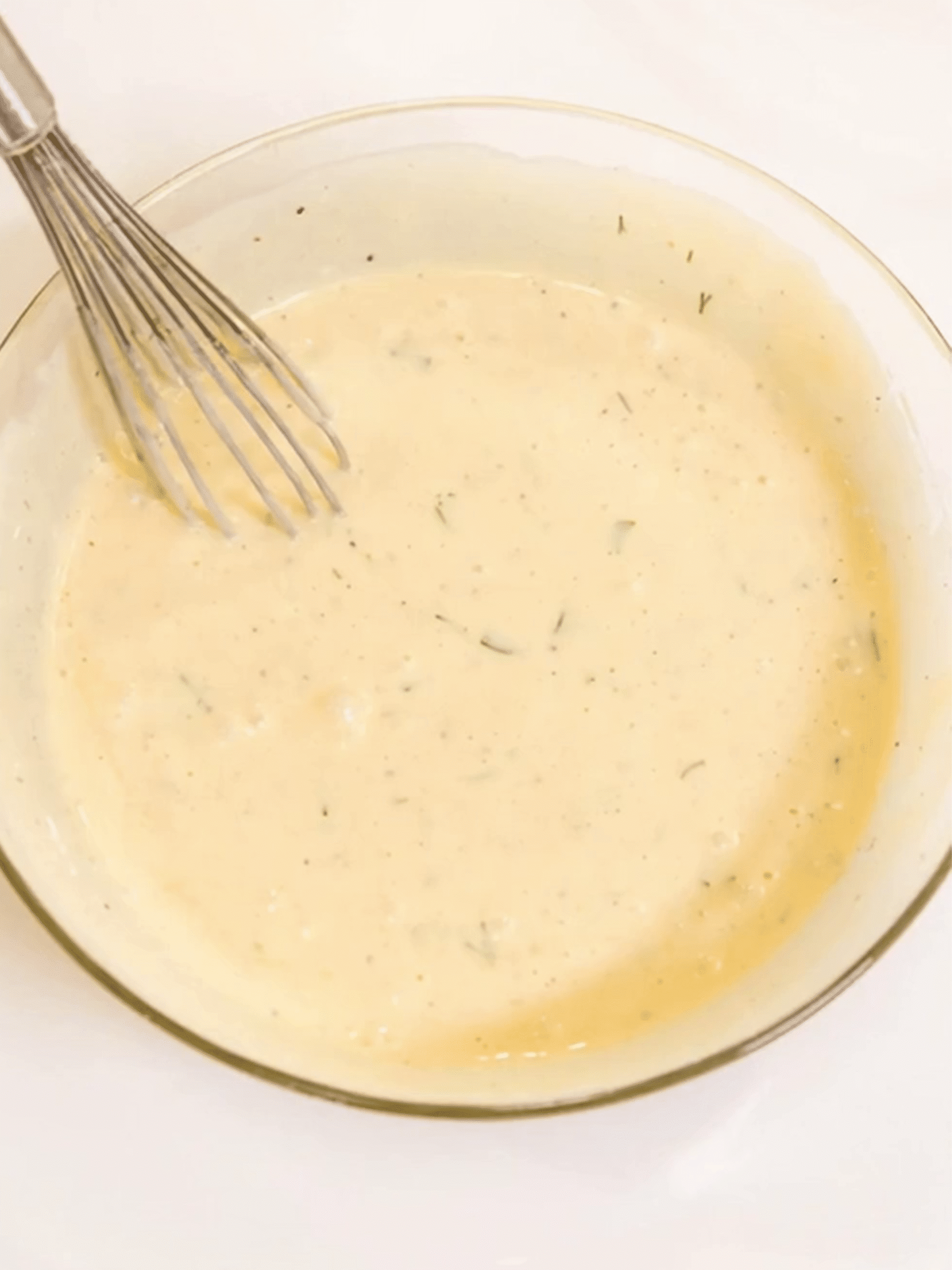Creamy Pasta Salad Dressing with Herbs and Lemon Creamy homemade dressing in a glass bowl with a whisk, ready for pasta salad