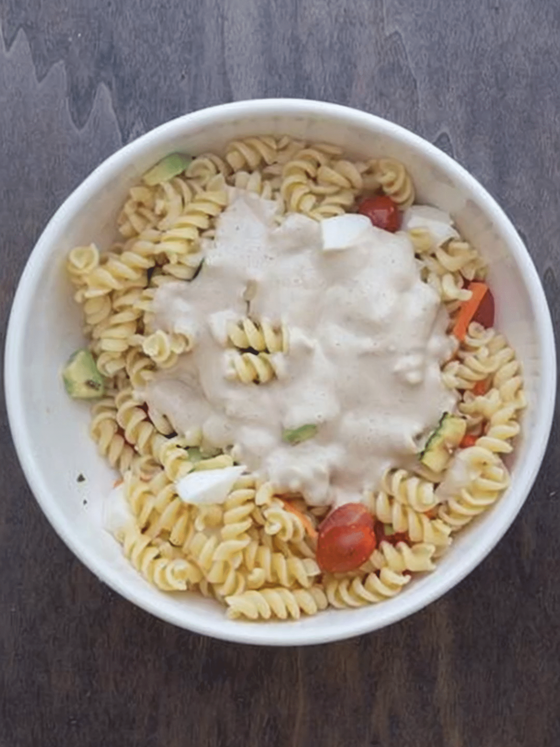 Creamy Italian Pasta Salad Before Mixing Bowl of rotini pasta with vegetables and creamy dressing on top