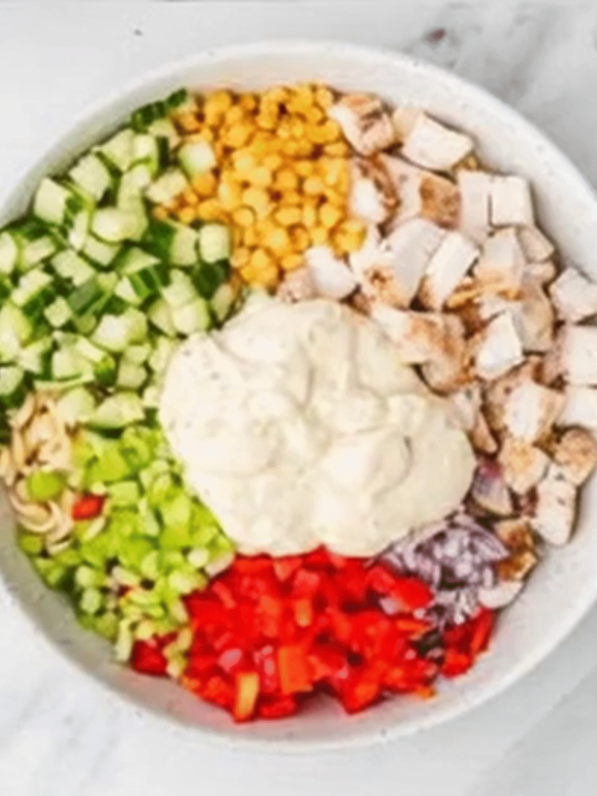 Chicken Ranch Pasta Salad Before Mixing Unmixed chicken ranch pasta salad ingredients with creamy dressing on top in a large white bowl