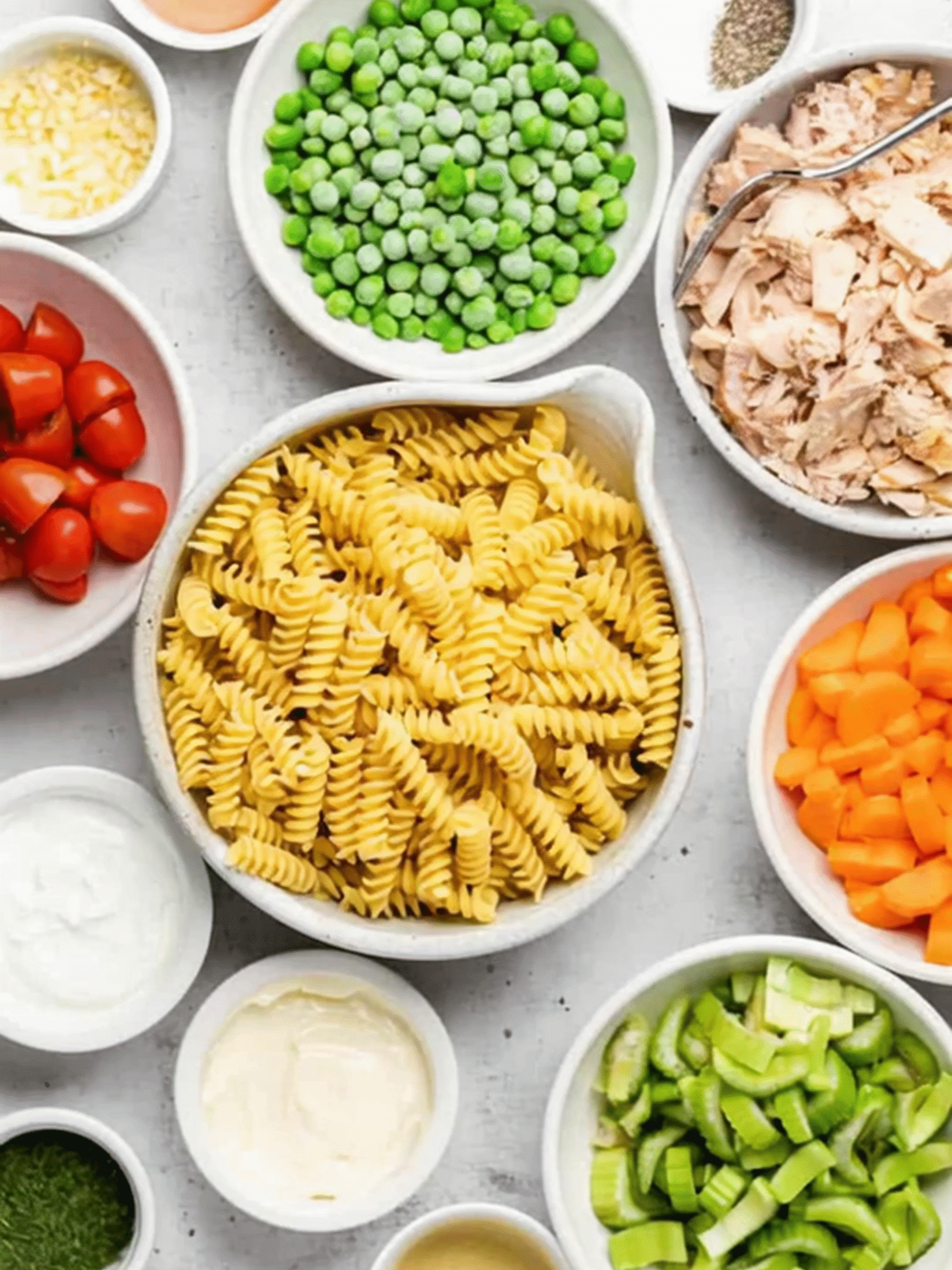 Ingredients for Tuna Pasta Salad with Creamy Dressing Fresh ingredients for creamy tuna pasta salad arranged in bowls on a white surface