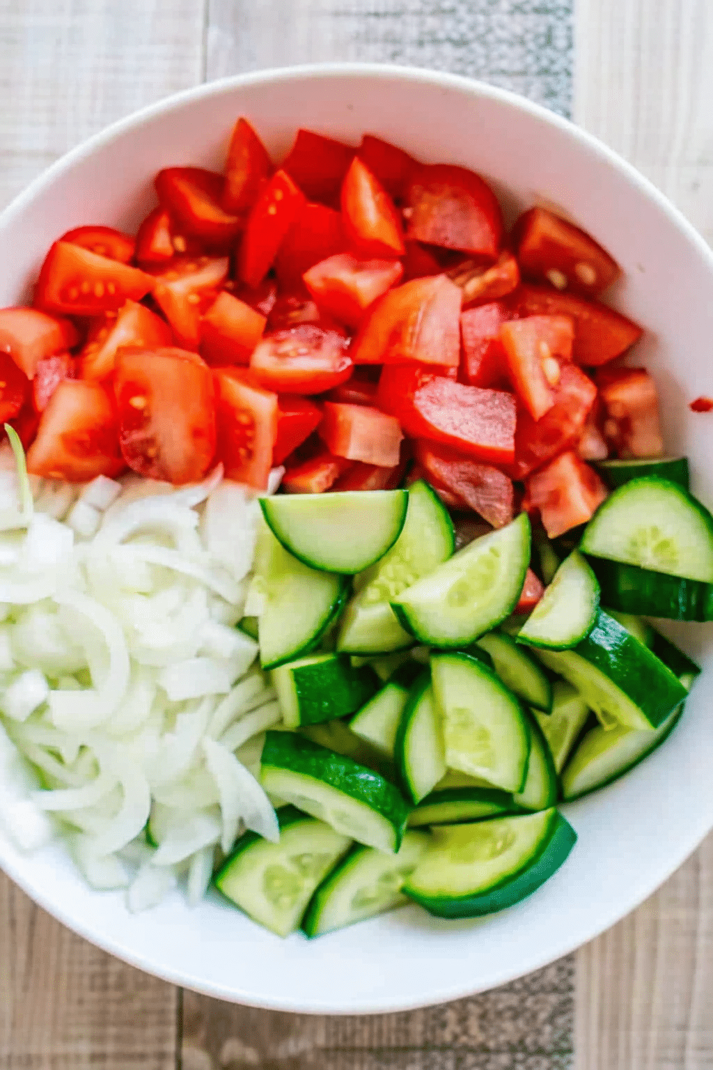 Fresh Chopped Cucumber, Tomato, and Onion Salad Ingredients Bowl of freshly chopped cucumbers, tomatoes, and onions ready for salad preparation.