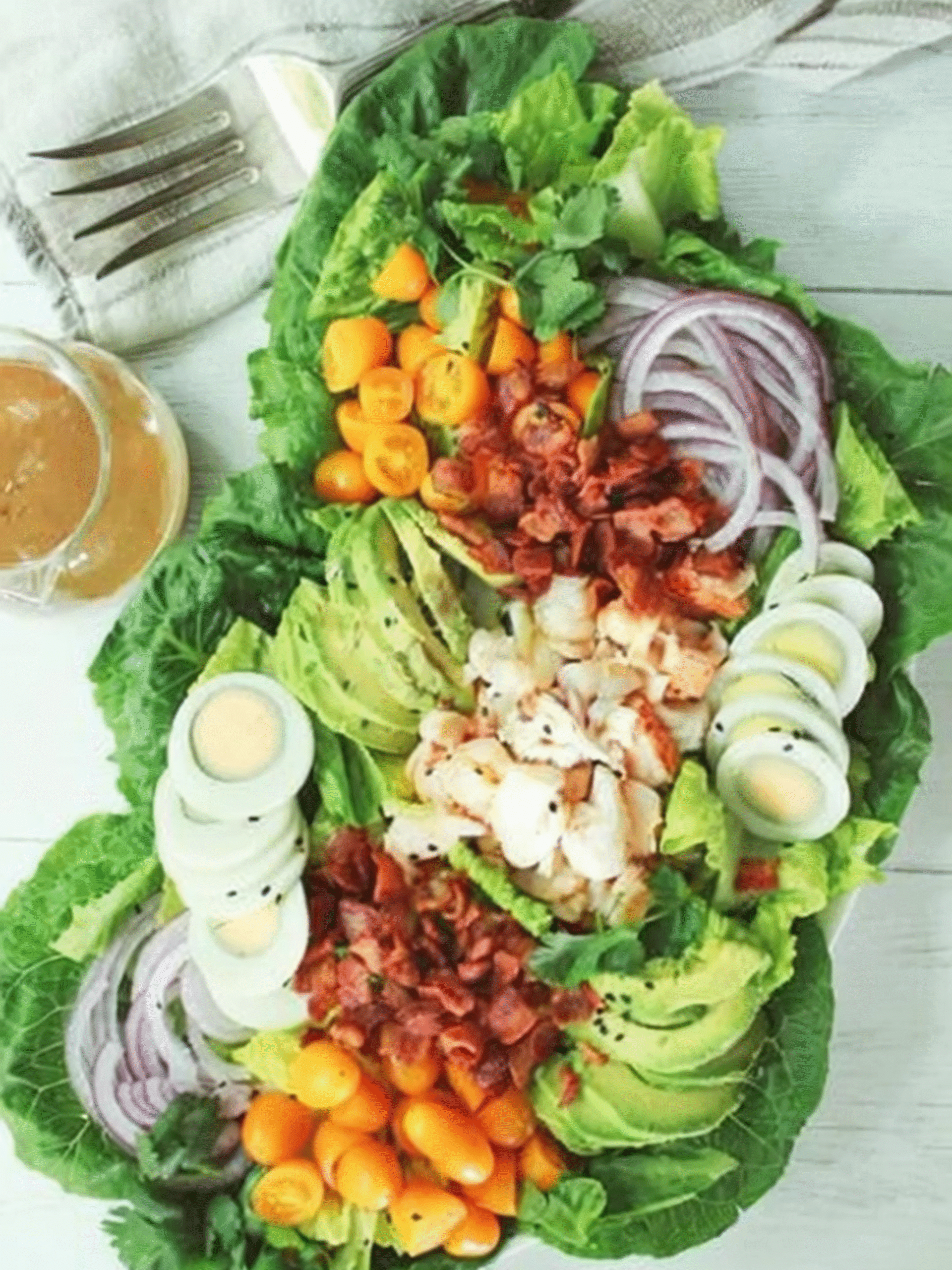Lobster Cobb salad with avocado, hard-boiled eggs, tomatoes, red onions, and miso dressing on a bed of lettuce