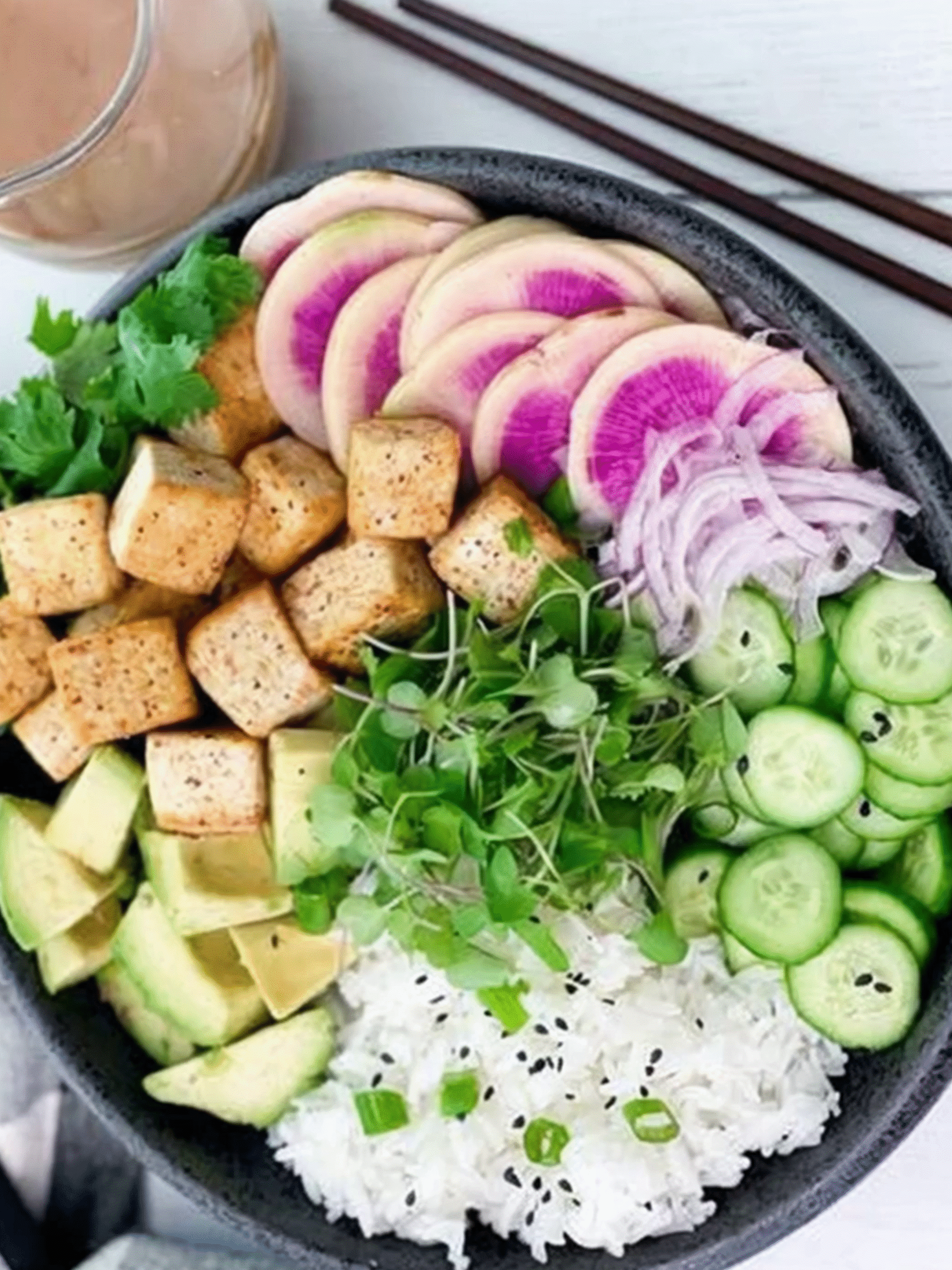 Seared miso tofu poke bowl with rice, avocado, cucumber, radish, and microgreens in a black bowl