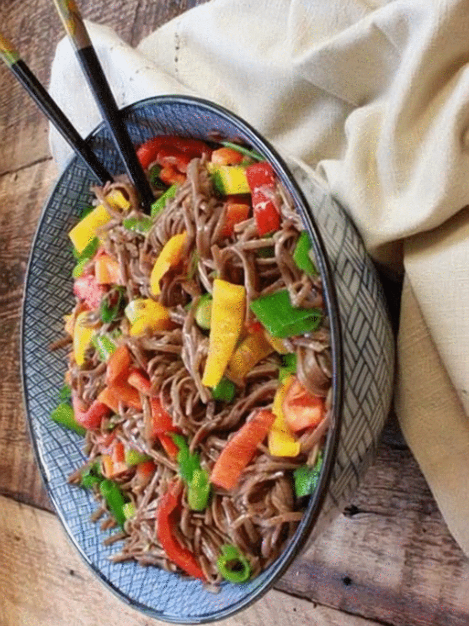 Colorful soba noodle salad with bell peppers and scallions in a patterned bowl
