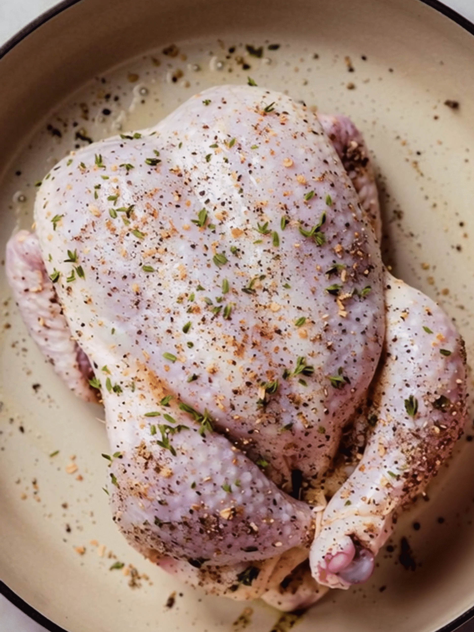 Pink Salt Seasoned Roasted Chicken Preparation with Fresh Herbs Raw whole chicken seasoned with Himalayan pink salt, black pepper, garlic, and fresh thyme, placed in a roasting pan ready for cooking.
