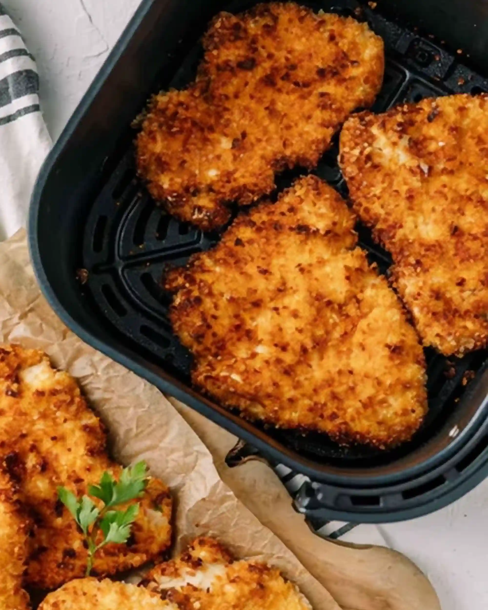 Golden crispy chicken breasts cooking in an air fryer basket with breadcrumb coating