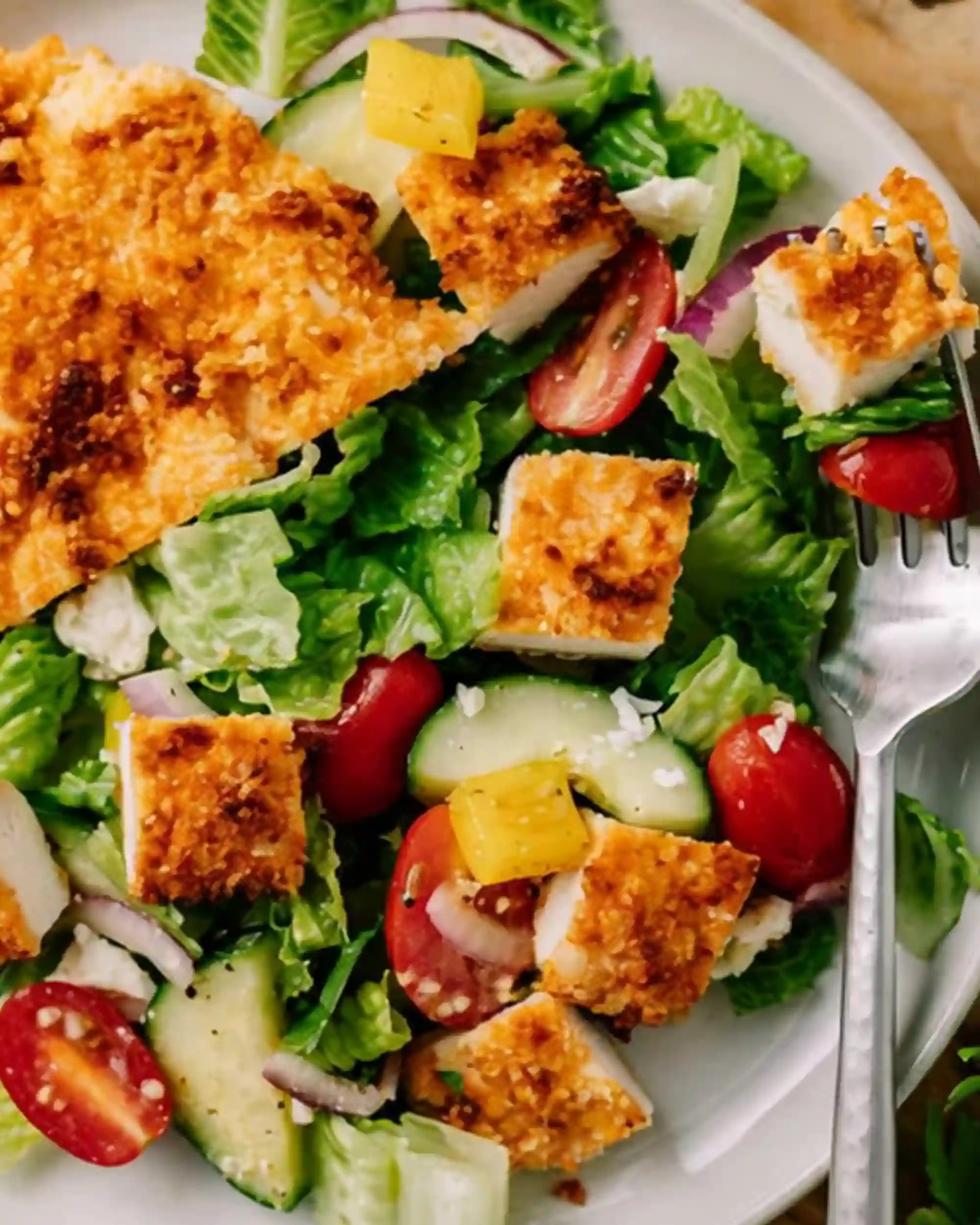 Crispy air fryer chicken breast served over a fresh garden salad with tomatoes, cucumbers, and lettuce