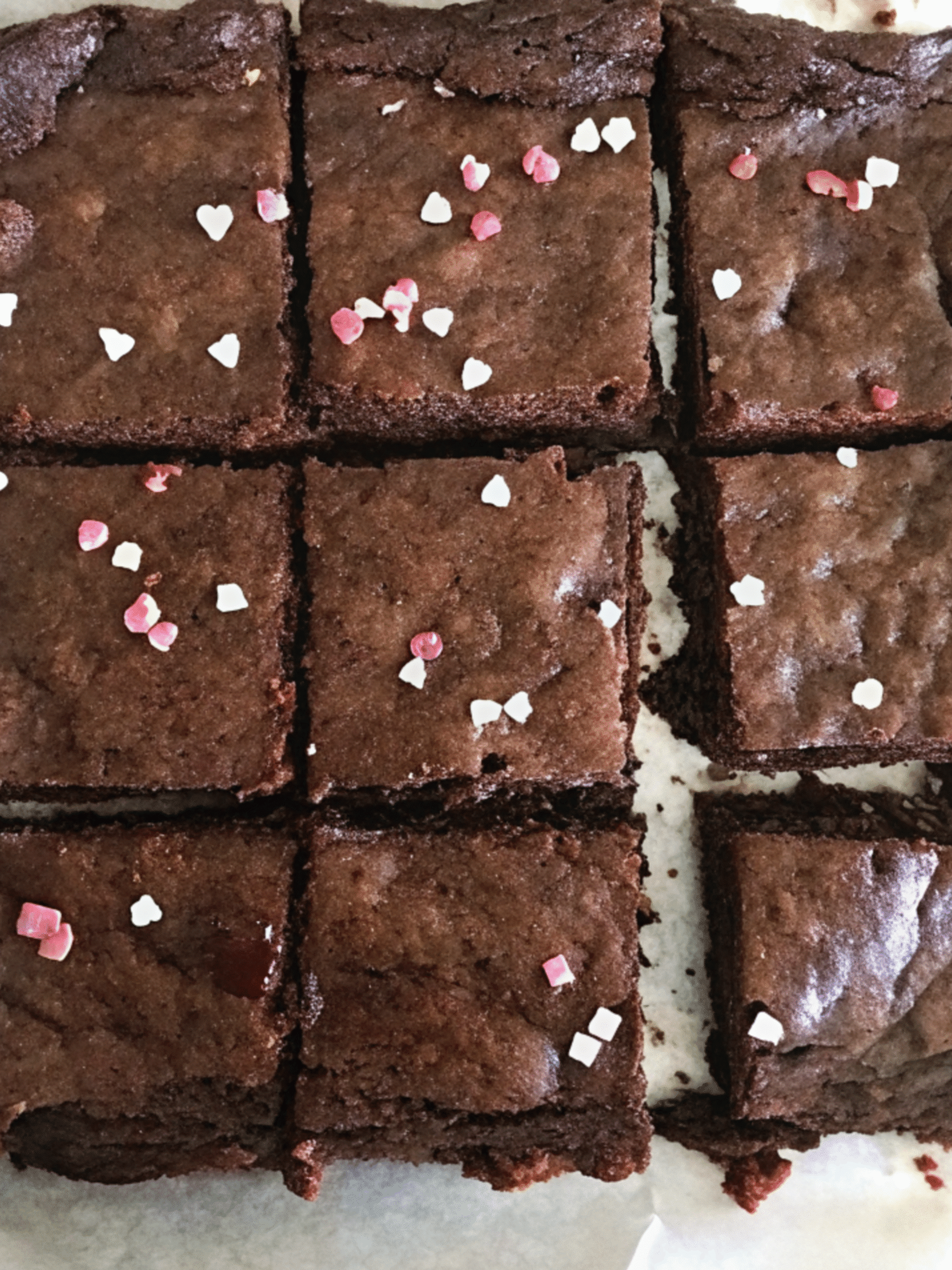 Fudgy pink salt brownies cut into squares with heart sprinkles