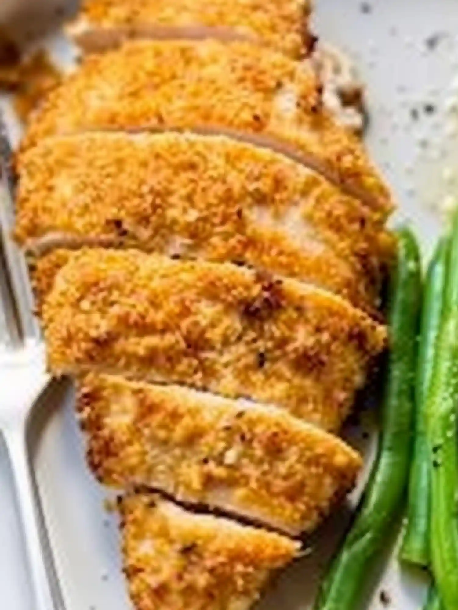 Crispy Breaded Air Fryer Chicken Breast Served with Vegetables Sliced crispy air fryer chicken breast with green beans