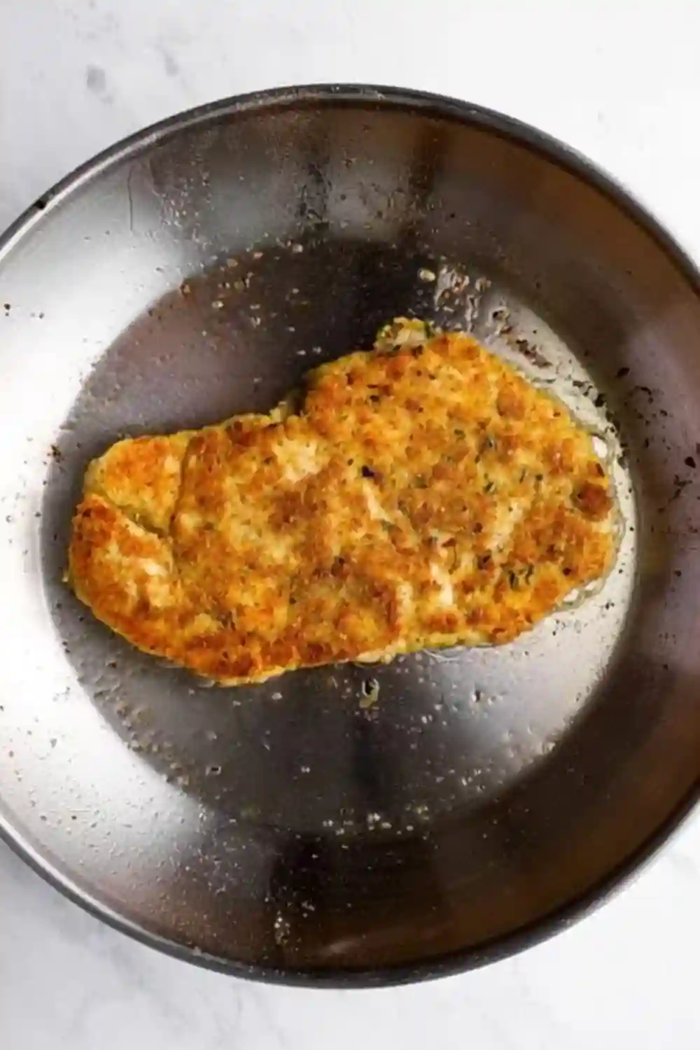 Pan-Fried Parmesan Crusted Chicken Cooking in a Skillet Golden Parmesan Crusted Chicken cutlet frying in a skillet with sizzling oil