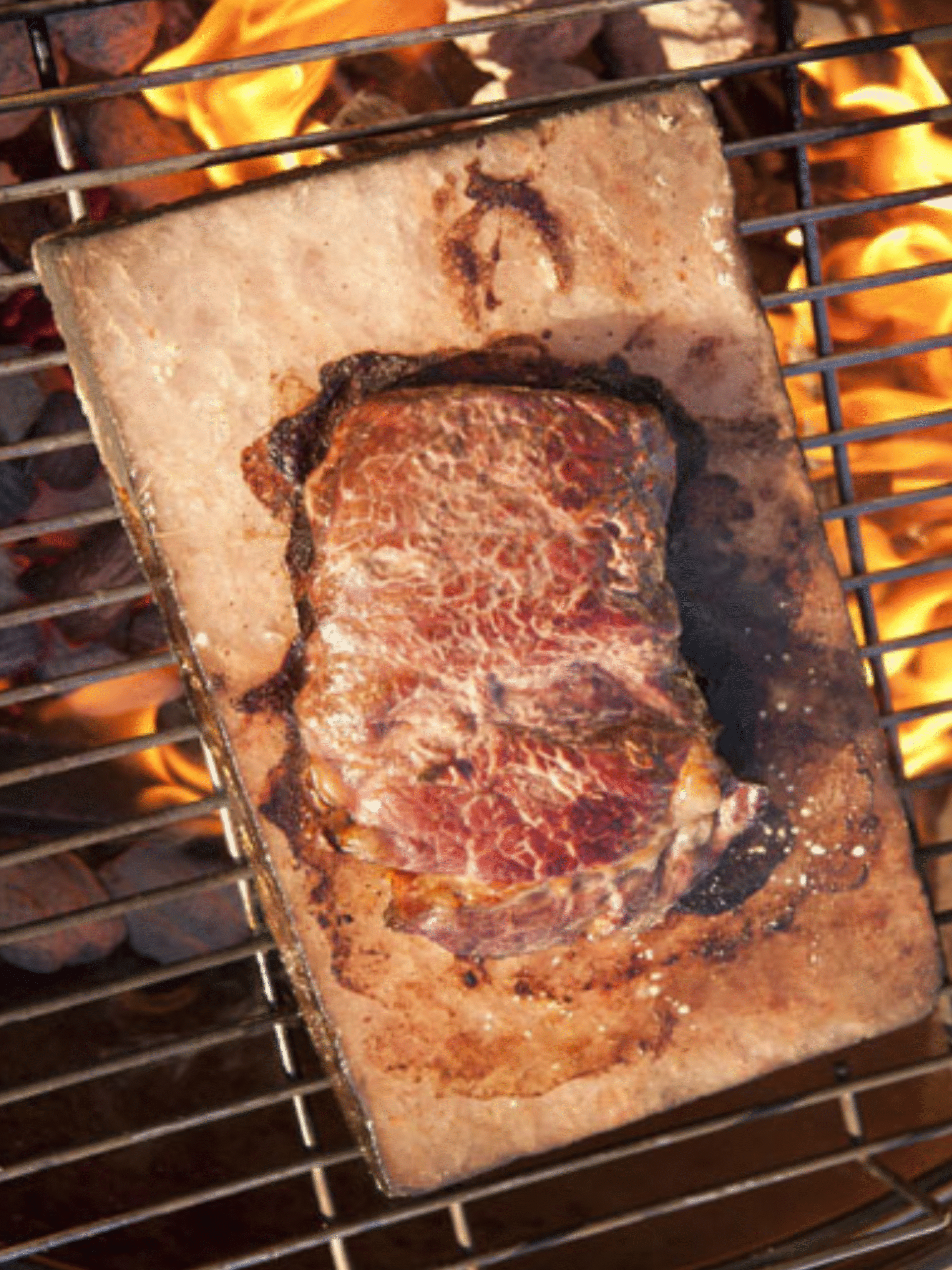 Grilling Steak on a Pink Salt Block Over Fire Steak grilling on a hot pink salt block over open flames for Pink Salt Grilled Steak