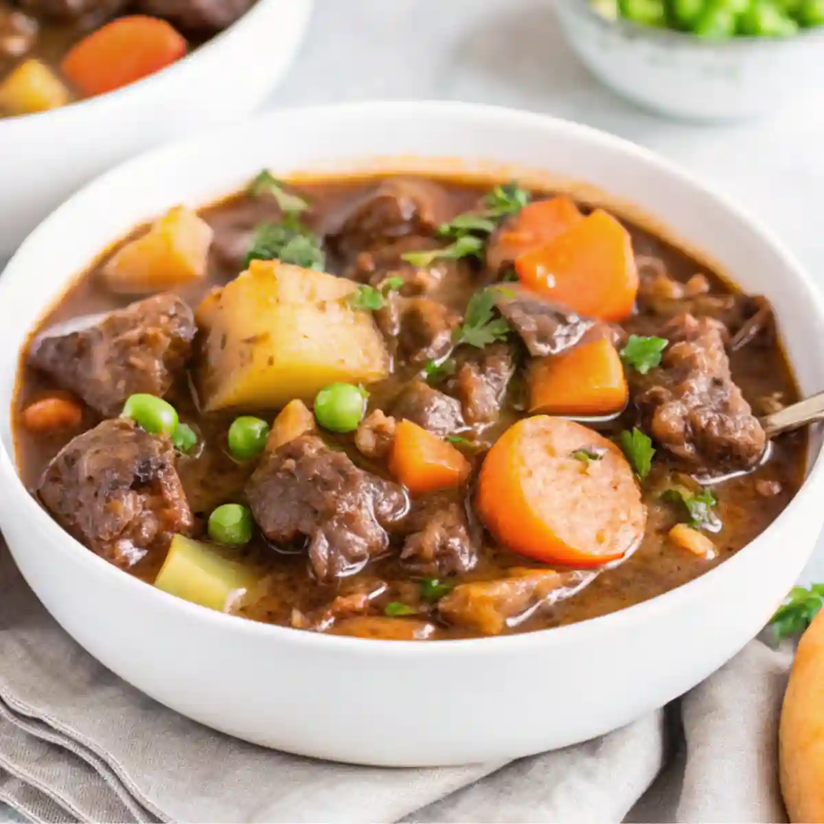 A hearty bowl of slow cooker stew recipes with tender beef, carrots, potatoes, and peas served in a warm, comforting broth