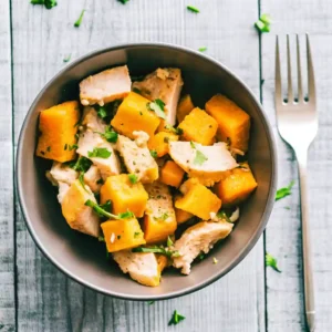 Bowl of roasted one pan chicken and butternut squash with parsley on a wooden table