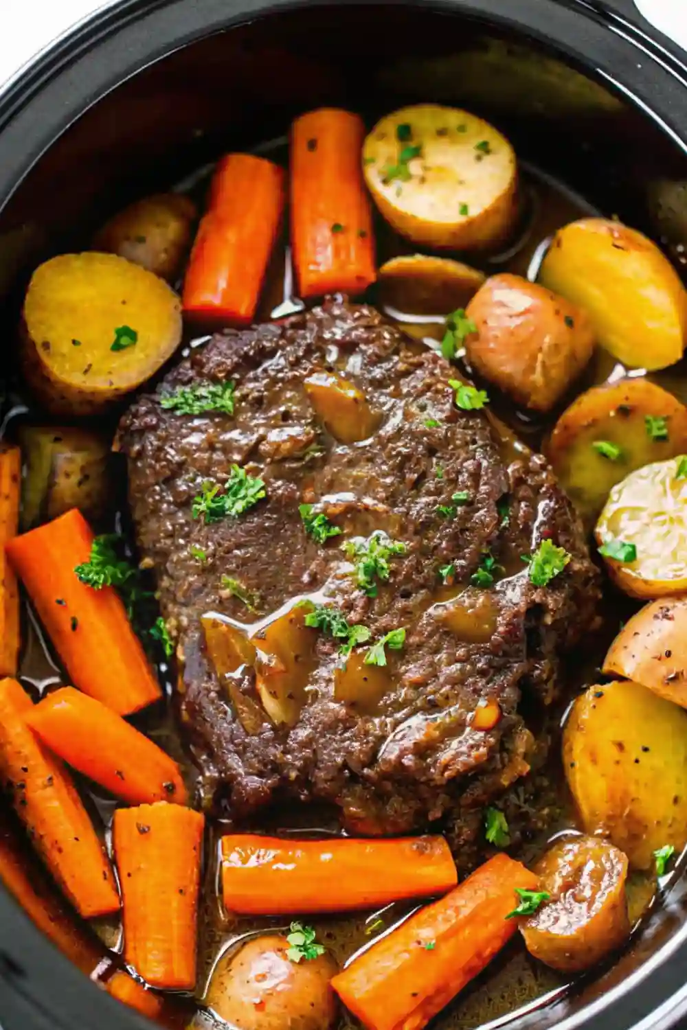 Beef roast crockpot recipe with carrots, baby potatoes, and gravy cooking in a slow cooker
