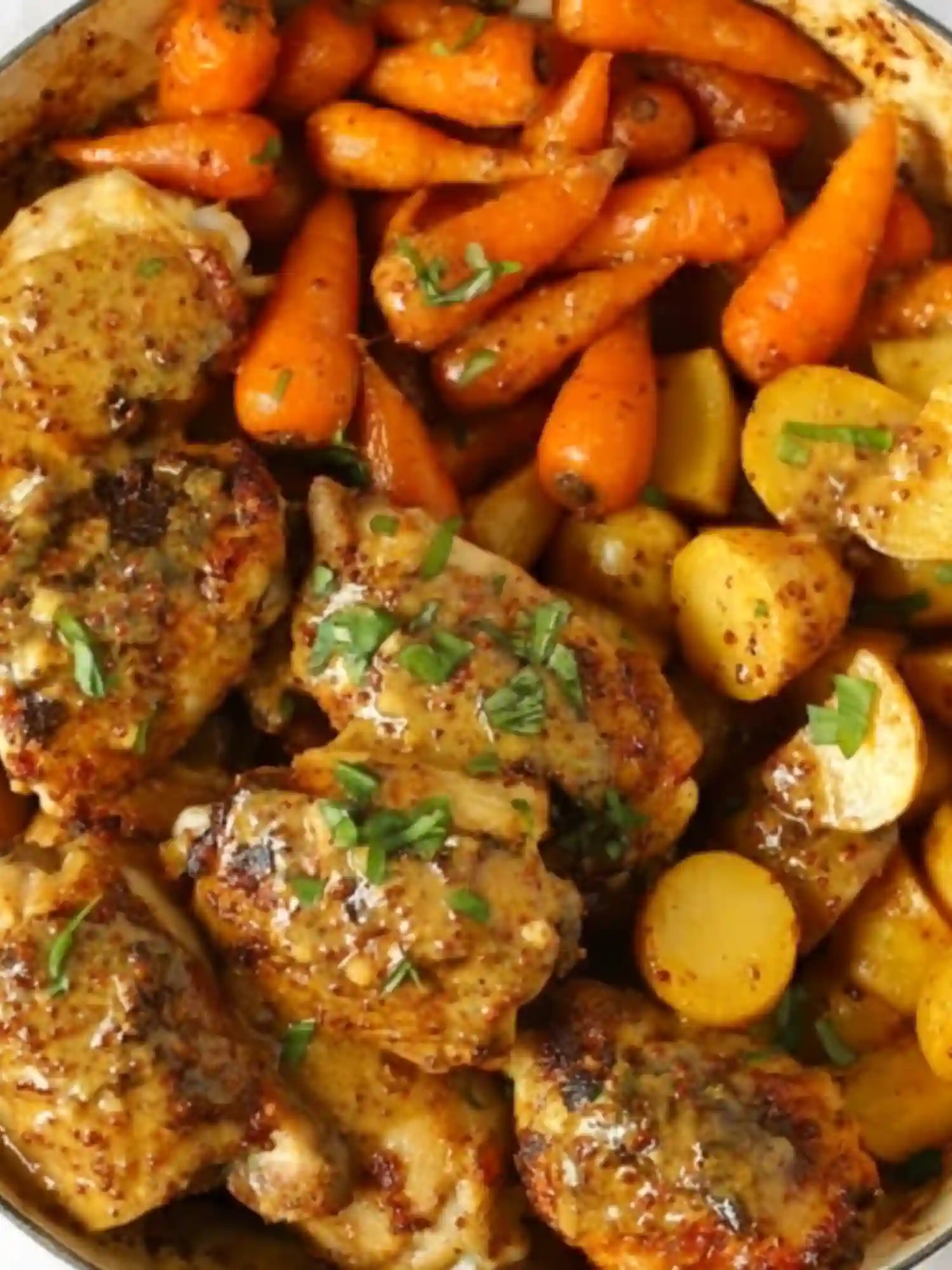 Honey mustard chicken thighs with roasted baby carrots and golden potatoes on a sheet pan, representing one of the chicken sheet pan recipes with sweet and savory flavors.