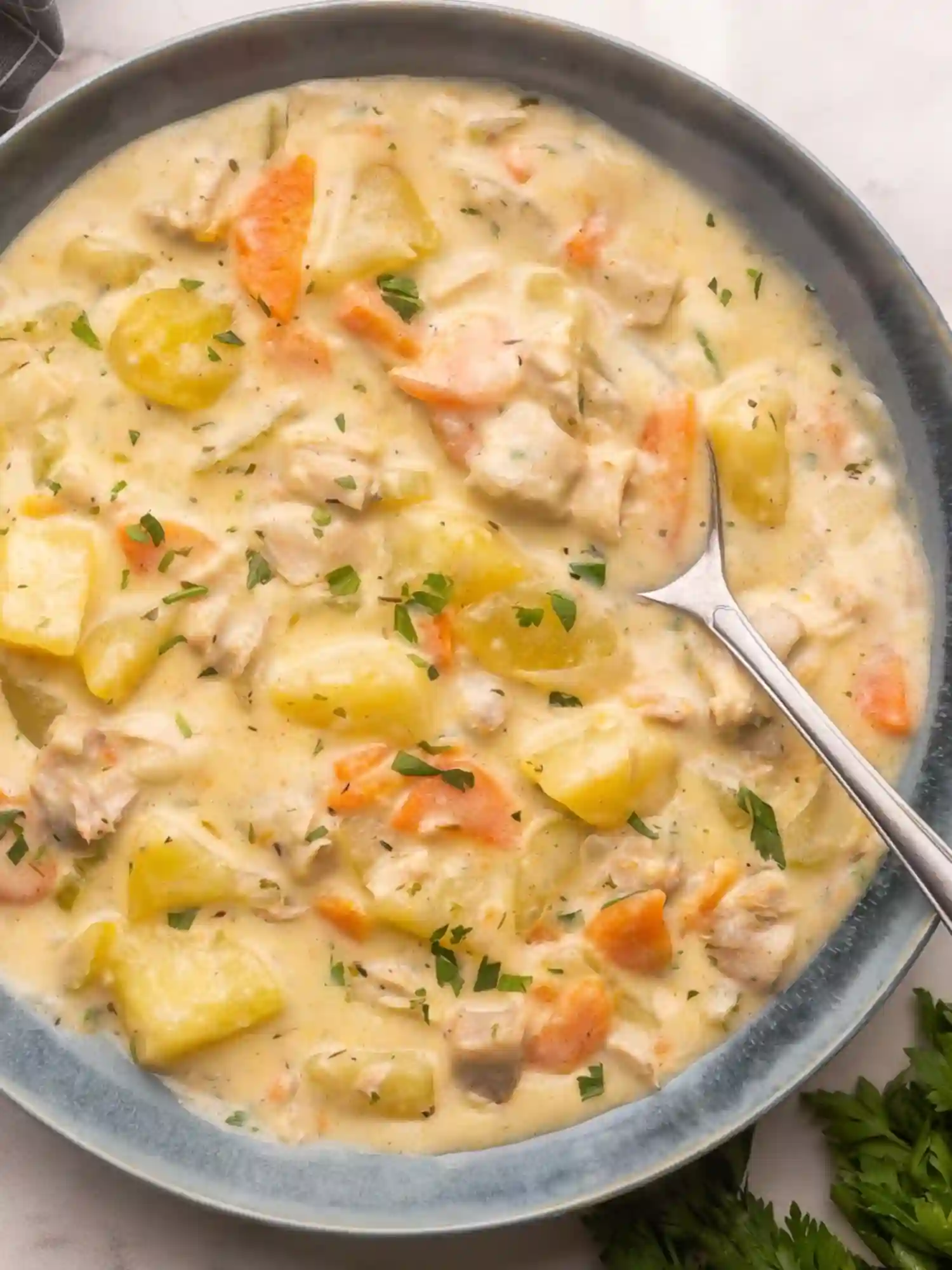 Bowl of creamy leftover turkey soup with potatoes, carrots, and fresh herbs.