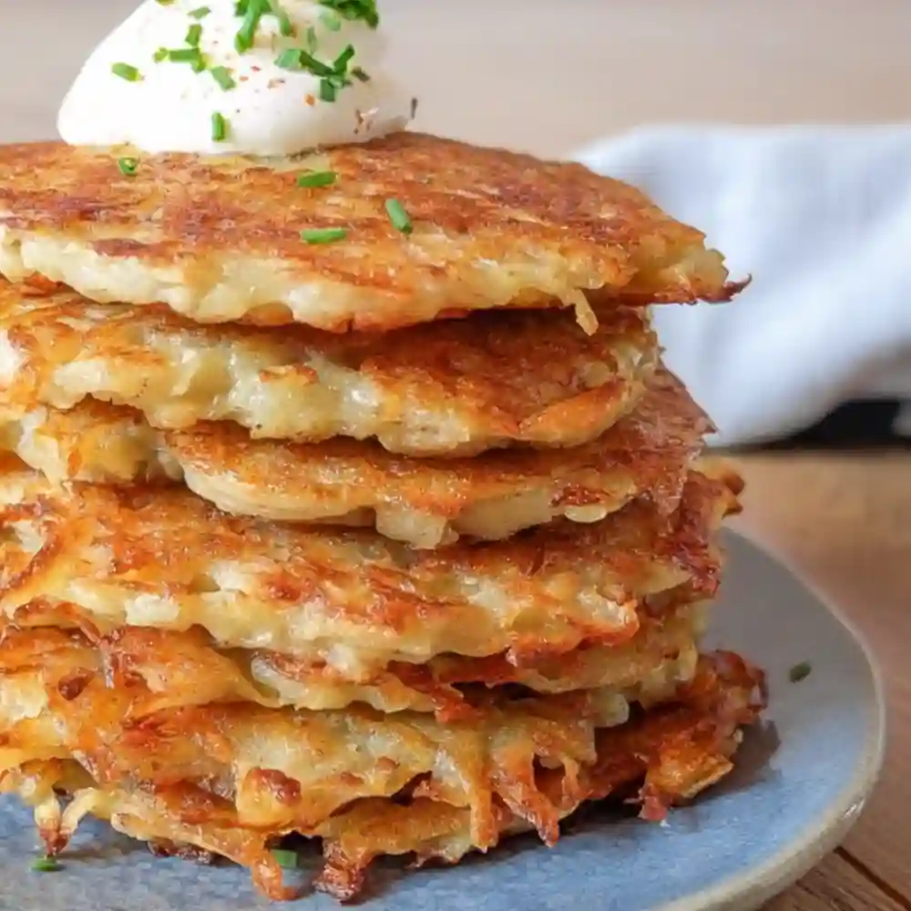 German Potato Pancakes Recipe served golden-brown with sour cream and chives on a blue plate