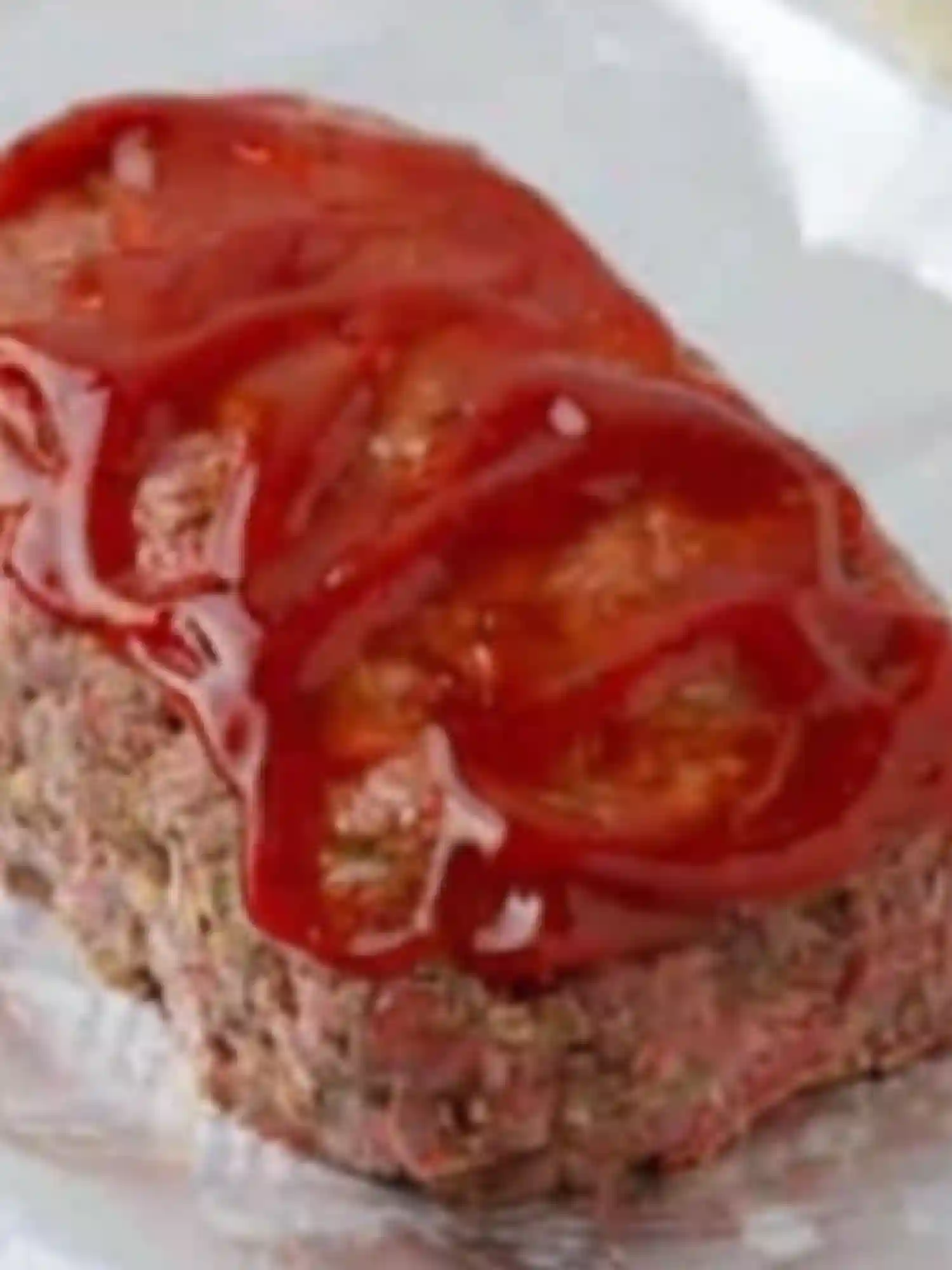 Whole loaf from classic meatloaf recipes topped with ketchup glaze on foil-lined pan