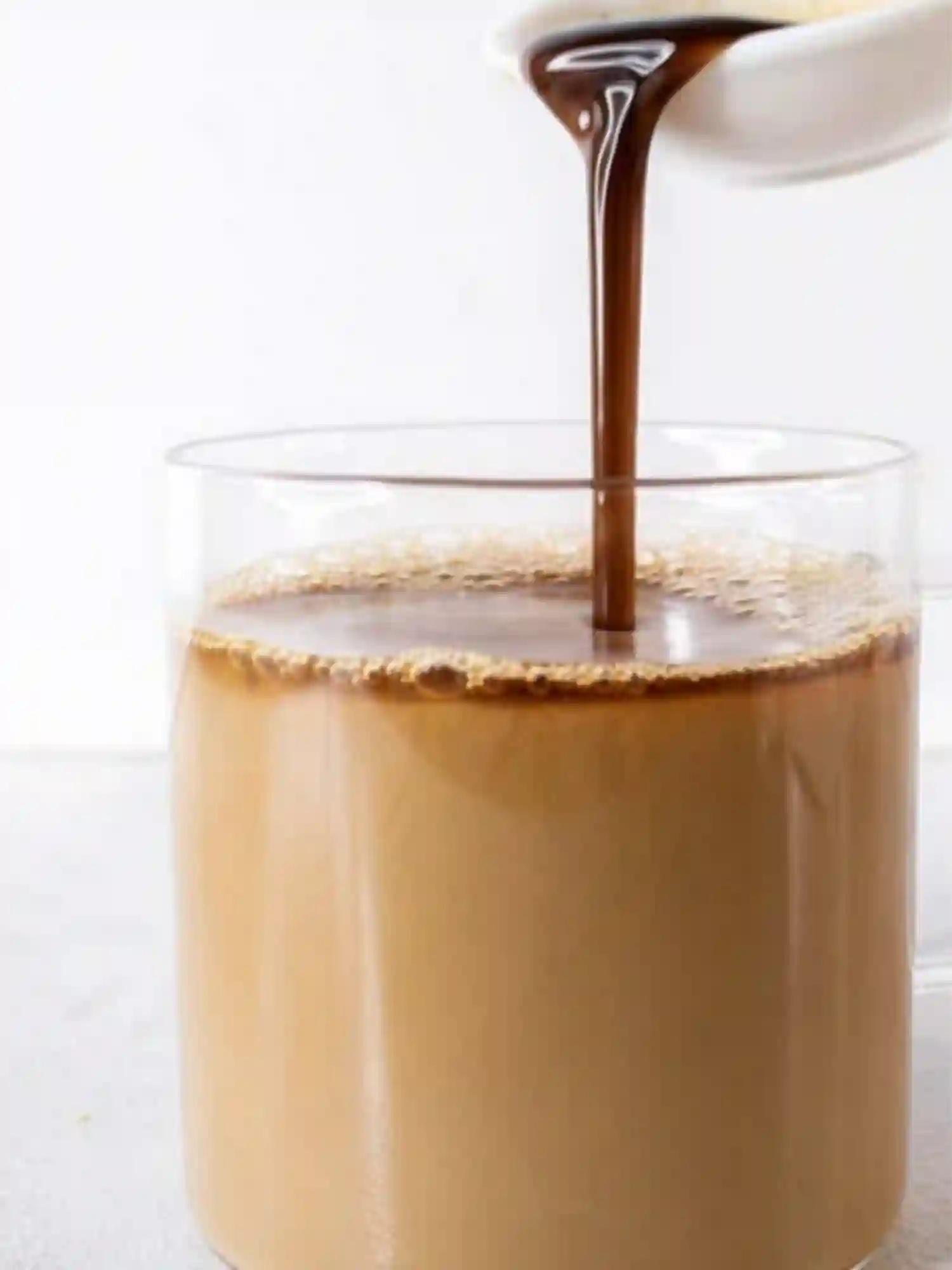 Pouring gingerbread syrup into a latte glass as part of a homemade Gingerbread Latte Recipe preparation.
