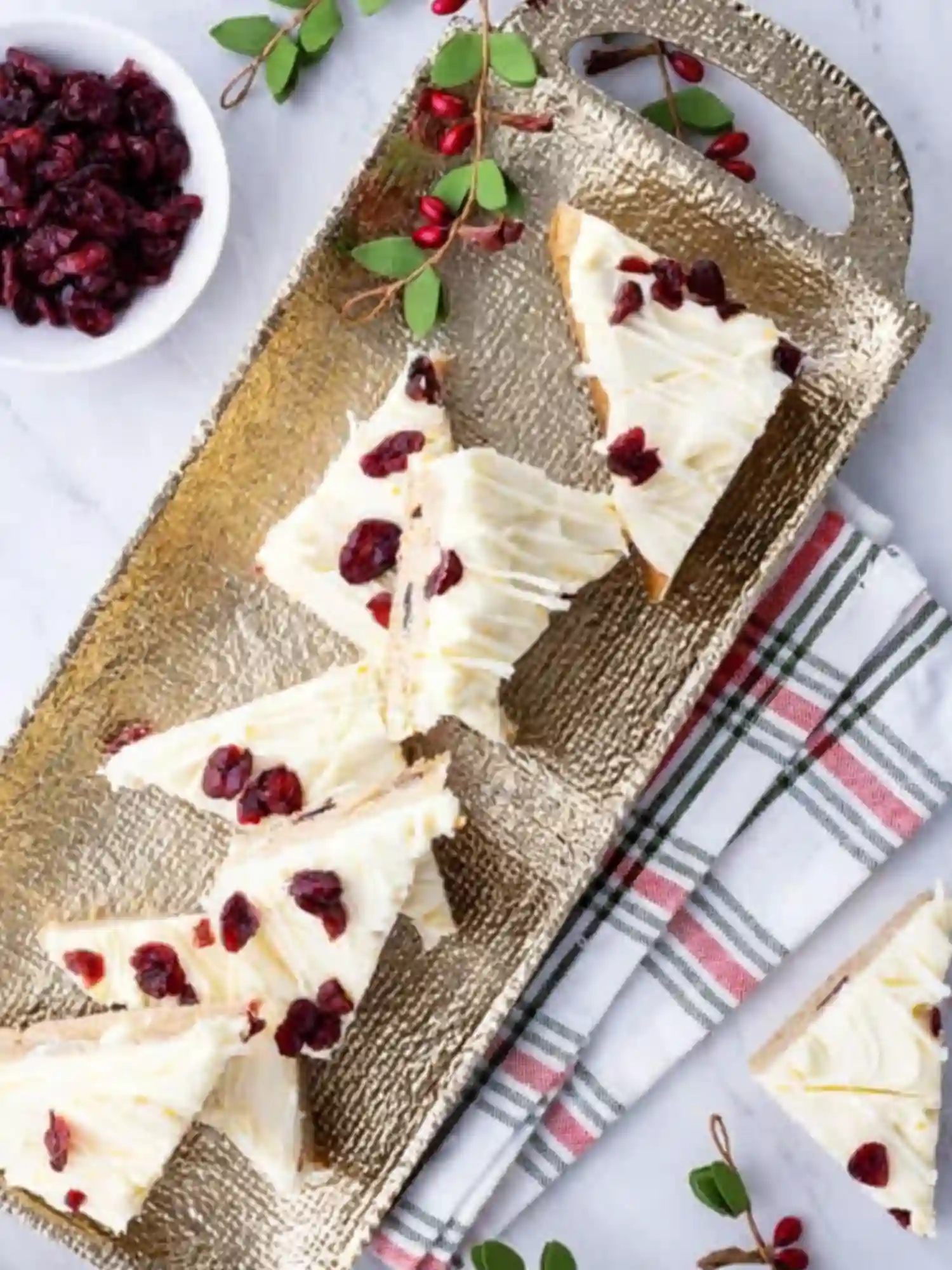 Holiday Presentation of Cranberry Bliss Bars Recipe Cranberry bliss bars recipe served on a festive golden tray with dried cranberries and holiday greenery