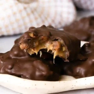 Homemade chocolate turtle candy showing gooey caramel and pecans inside a dark chocolate coating, perfect for chocolate candy recipes.