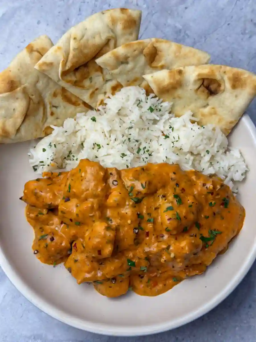 Plate of Butter Chicken with white rice and naan bread