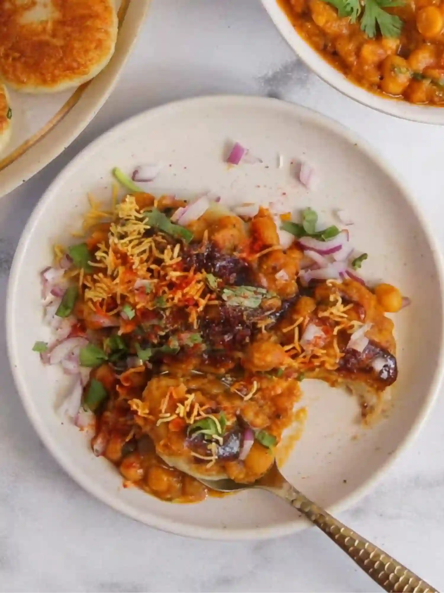 Ragda Patties Recipe Street Style Serving Ragda Patties Recipe served with white peas curry, sweet tamarind chutney, green chutney, chopped onions and sev in a bowl.