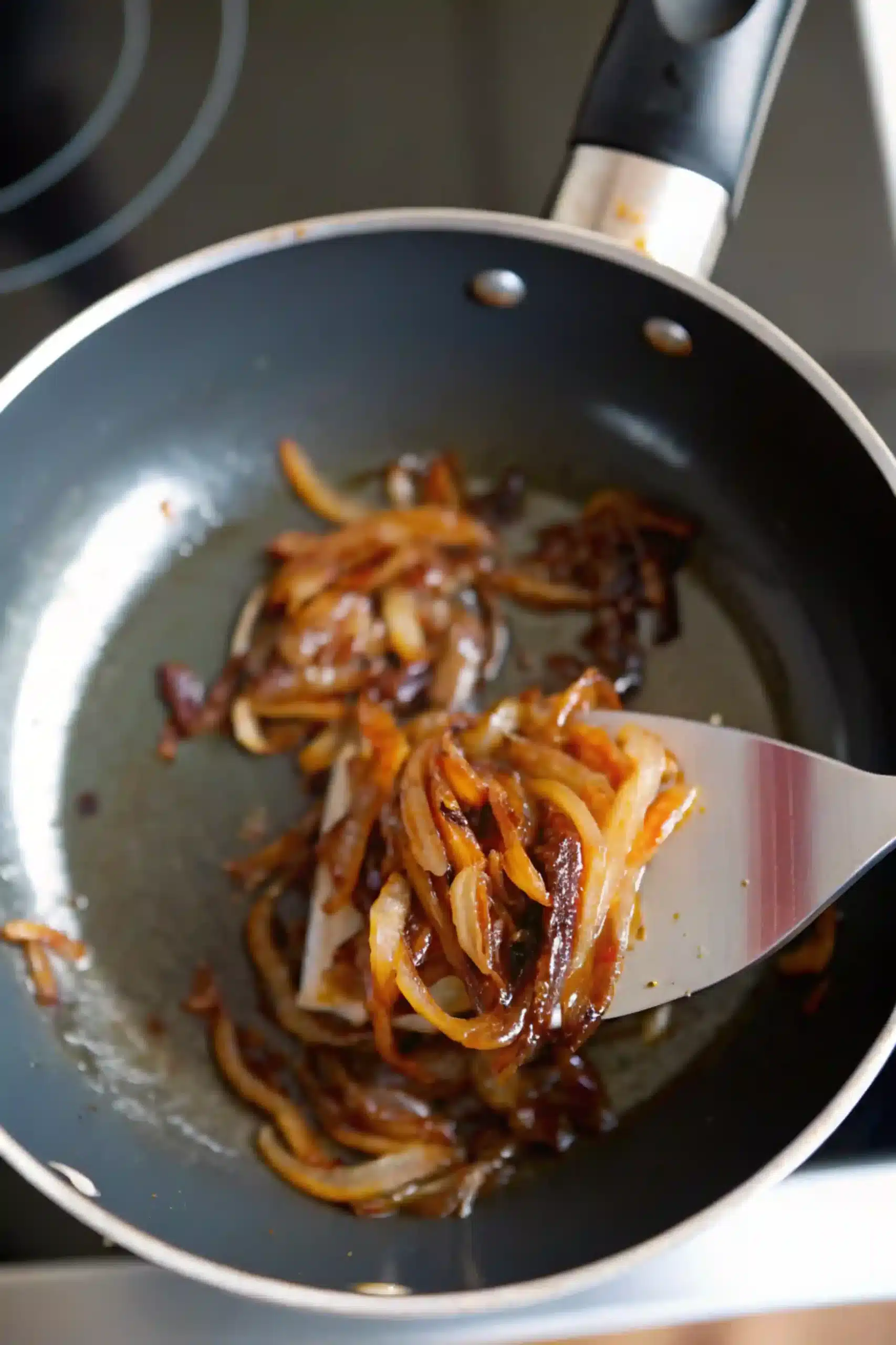 Caramelized Onions for Croissant Smash Burger Recipe caramelized onions cooking in pan for croissant smash burger recipe