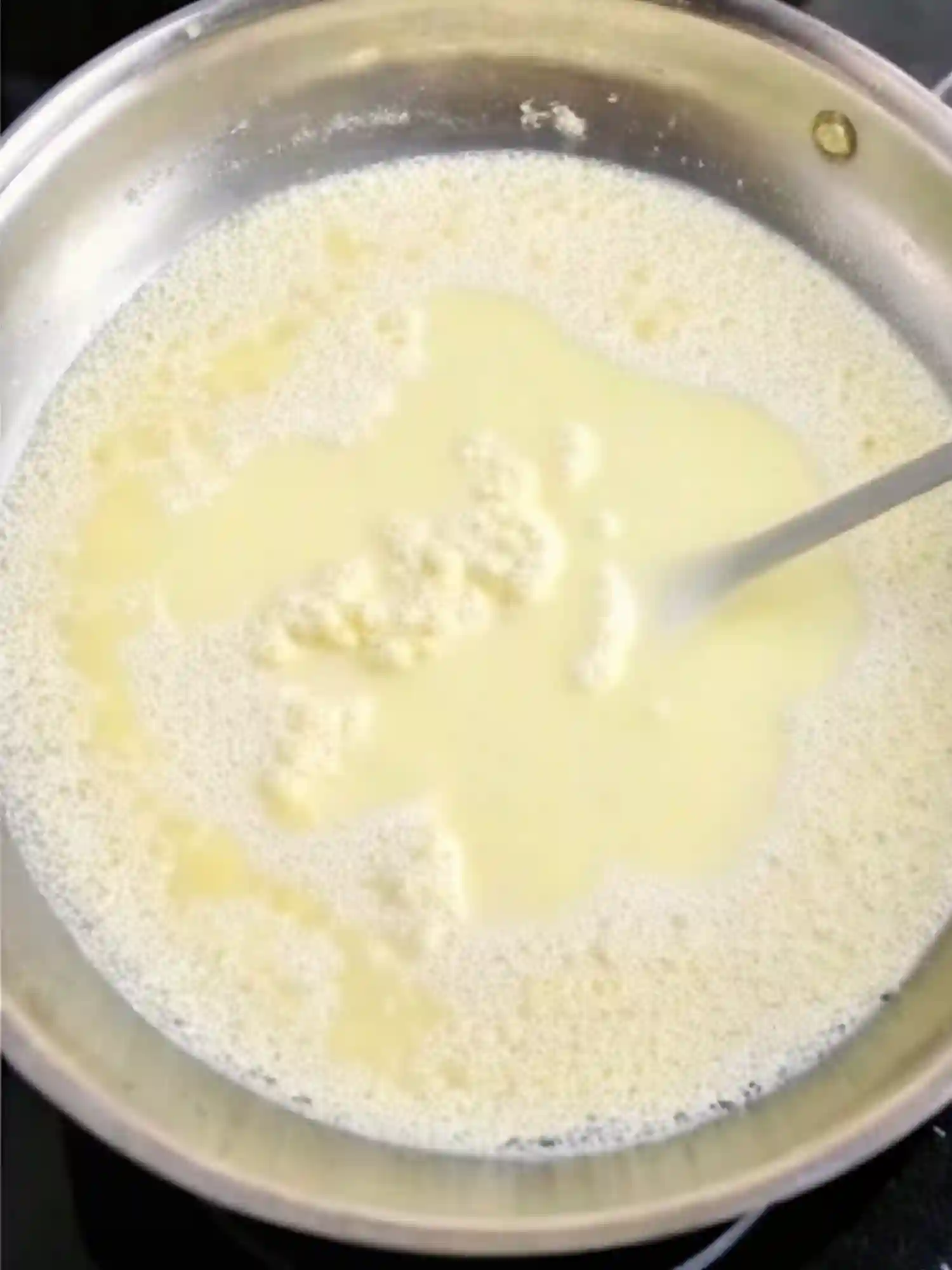 butter melting in milk in pan for creamy garlic parmesan pasta sauce