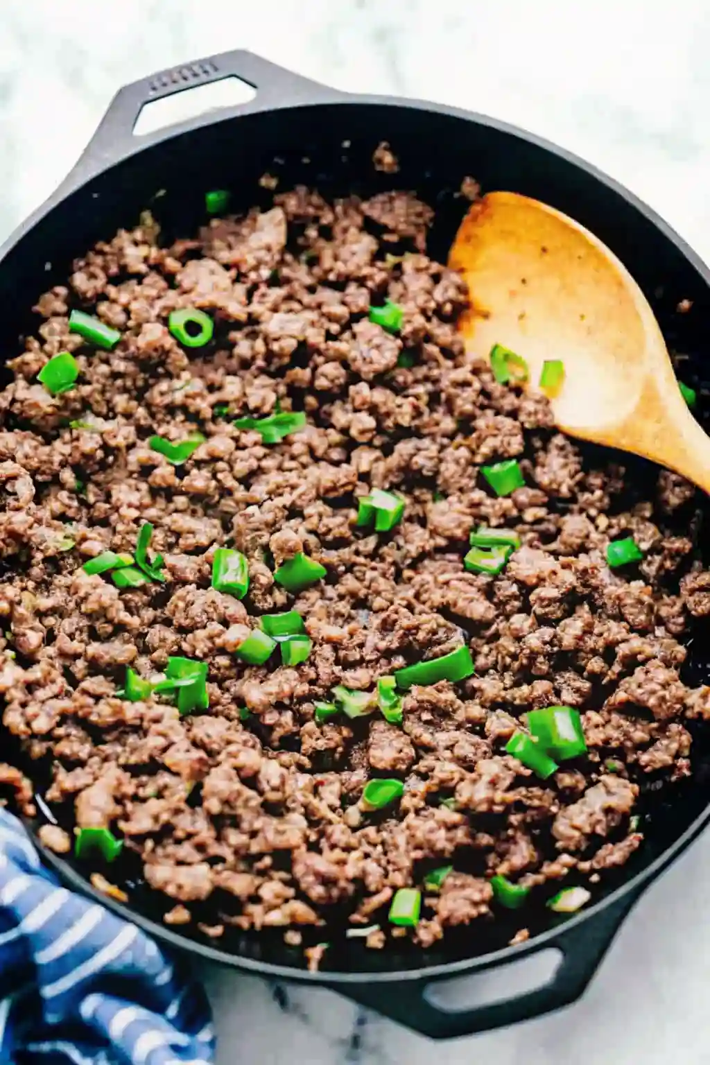 korean ground beef cooking in skillet with green onions